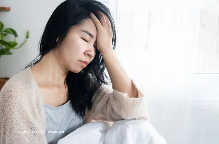 頭を抱えて疲れた表情の40代女性｜更年期の落ち込みや不安を和らげるアロマ活用術