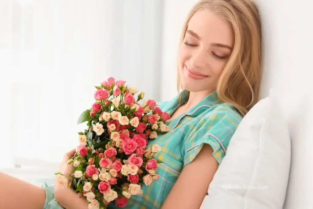 ローズの花束を抱え幸せな表情の女性｜ローズ精油の効果と使い方｜自己肯定感を満たし、女性性を整える夜の香り