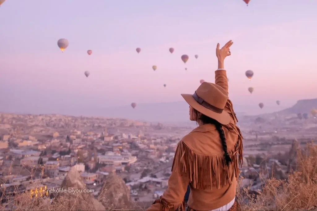 夕暮れ空に飛ぶ気球とそれを見渡す女性の写真|「根」を張る時間は終わりました。今、アロマと星で「太陽」を目指す旅へ